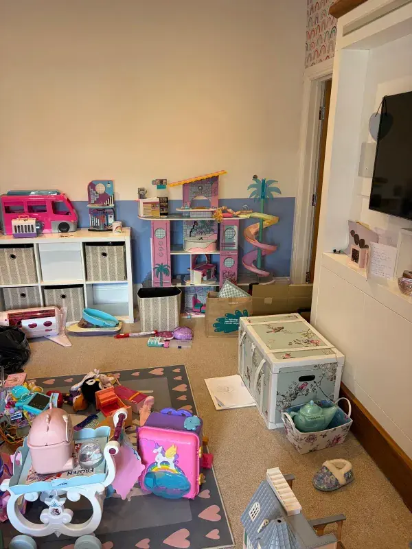 Children's playroom before organising, with toys spread across the floor and rug